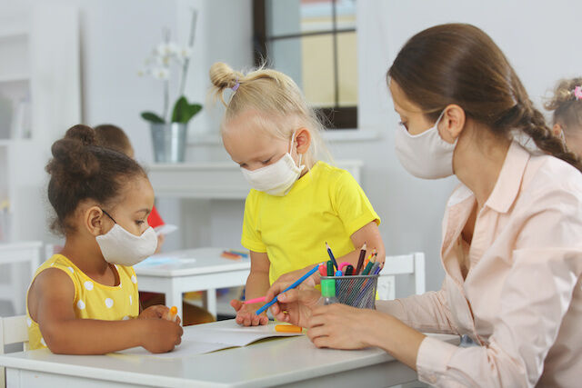 Teacher gives task to students with face mask